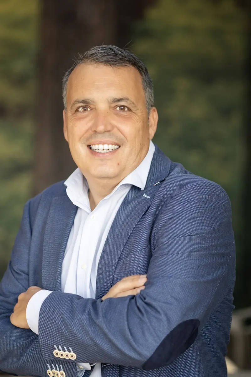 David Huerta sonriendo, con americana azul y los brazos cruzados